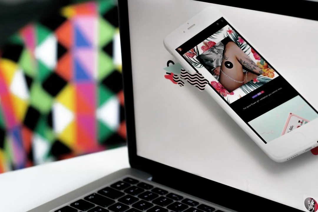 A man edits a fruit image on a MacBook Pro while sitting outdoors on grass.